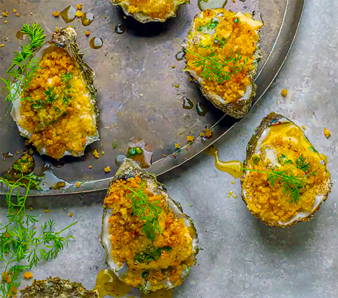 grilled oysters topped with fennel crumbs on a tray