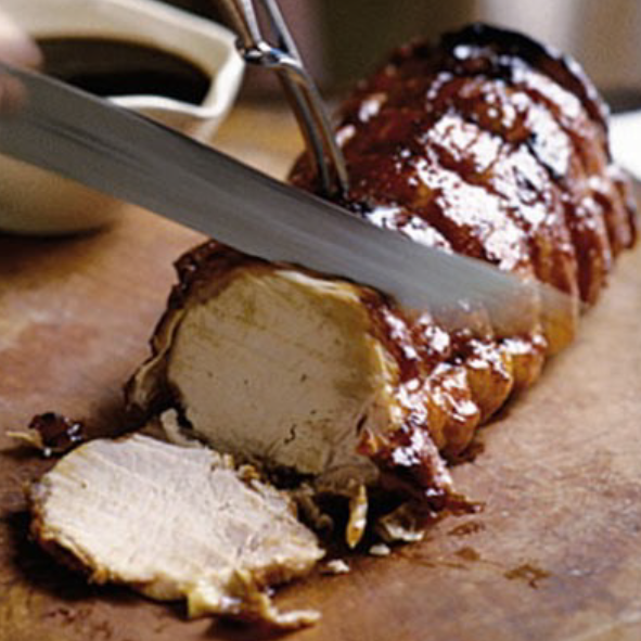 rolled pork loin glazed with honey and guinness slices on a chopping board