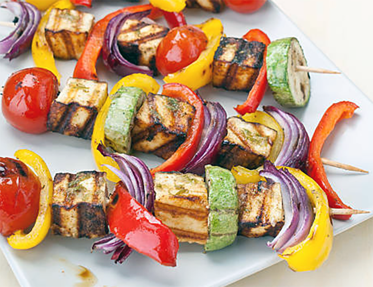 barbecued halloumi and vegetable kebabs on a chopping board