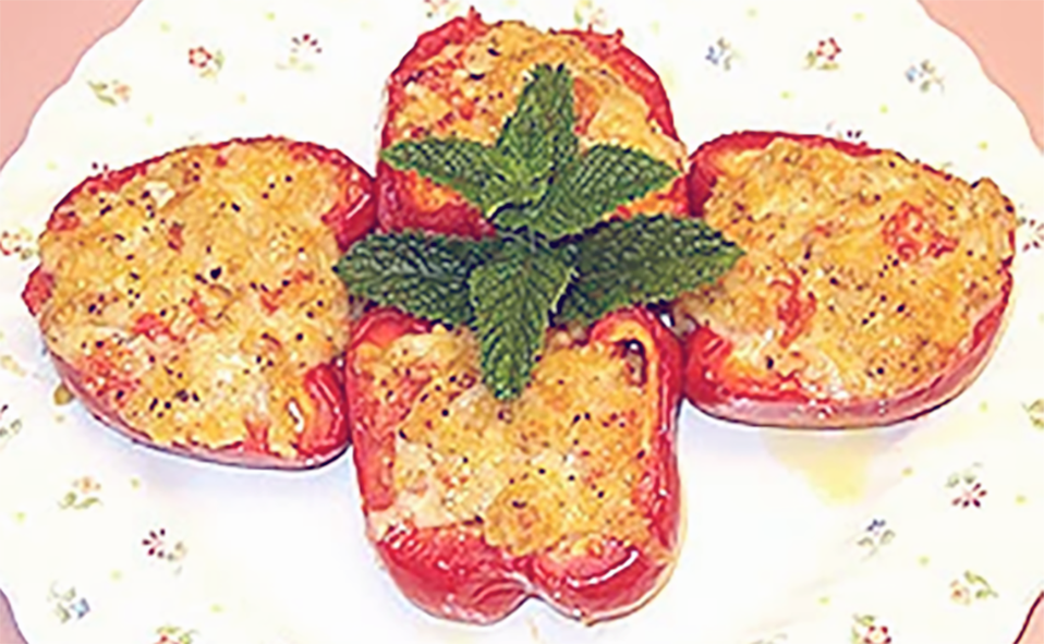 Four bell pepper halves arranged in a cross shape on a plate and stuffed with hashwe rice mix