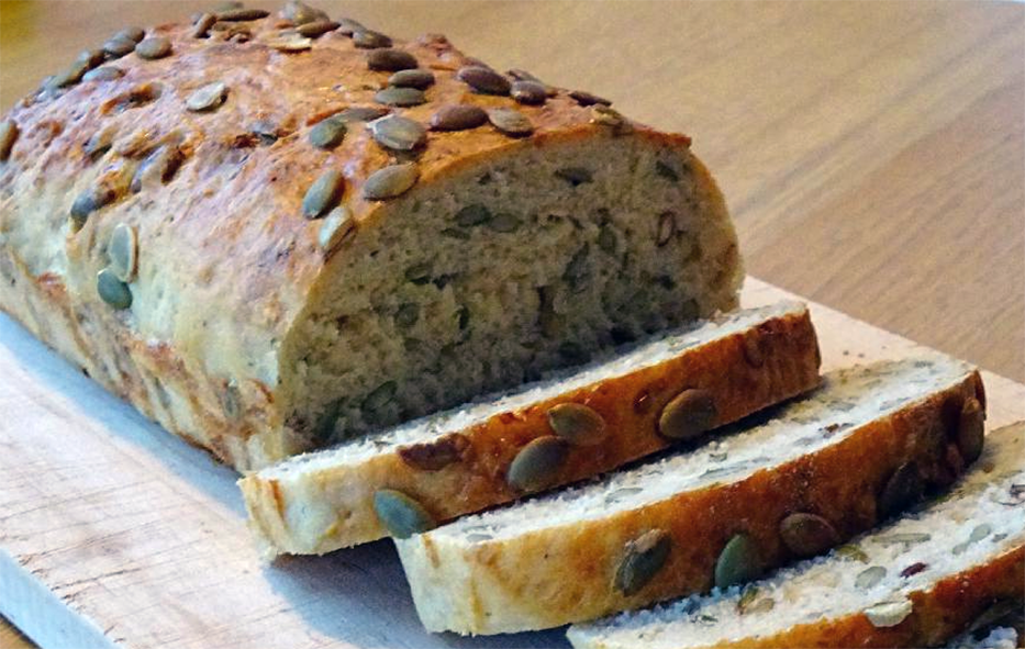 sliced pumpkin seed loaf on a chopping board
