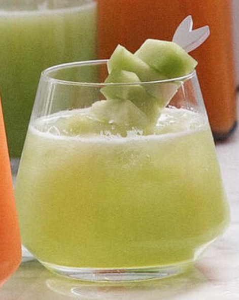 honeydew agua fresca in a glass with a garnish of honeydew chunks on a cocktail stick