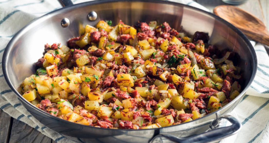 corned beef hash of corned beef, potatoes and onion in a frying pan