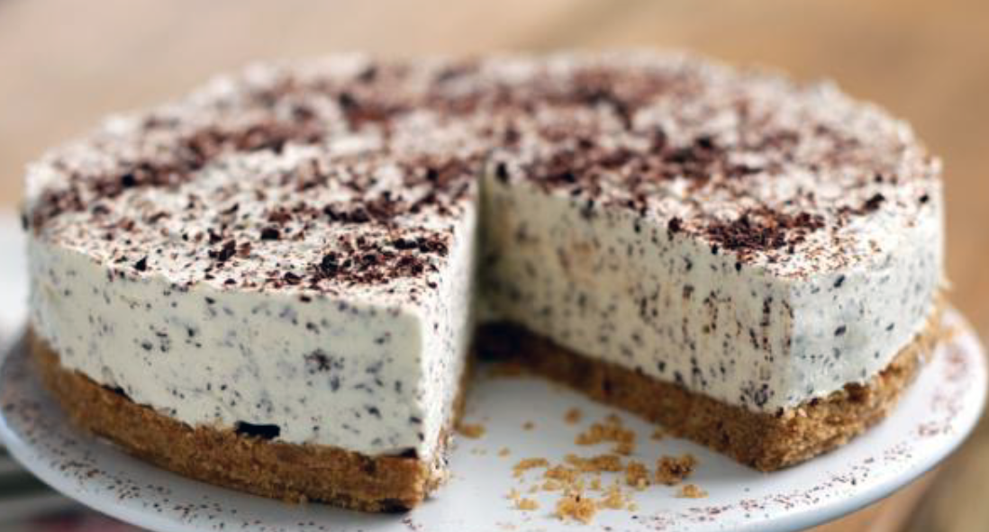 Irish cream and chocolate cheesecake on a cake stand with a wedge removed to reveal the base and filling