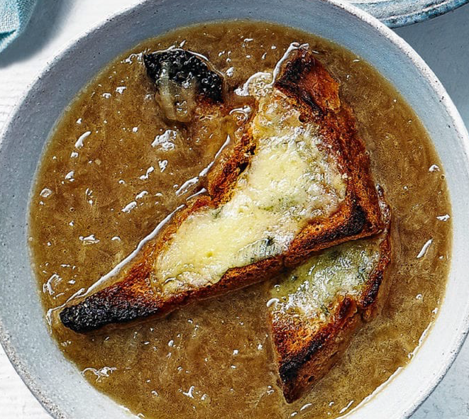 rich brown Irish onion soup in a bowl garnished with a triangle of toasted bread and cheese