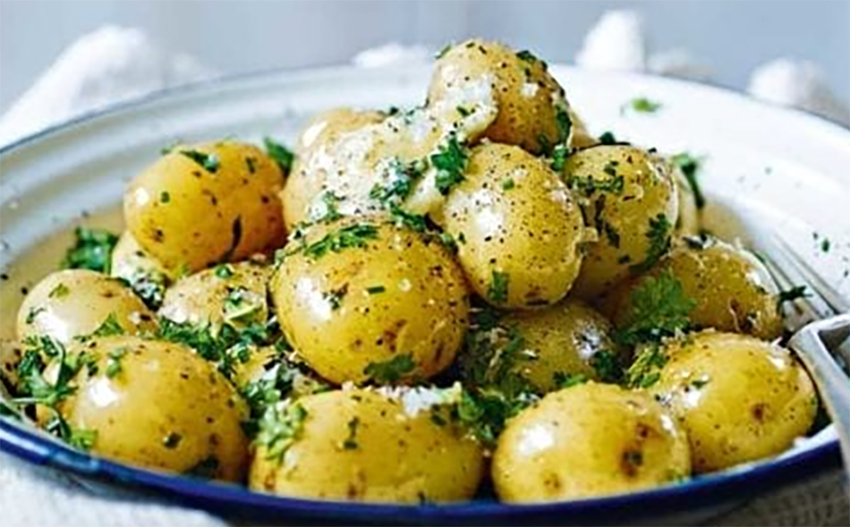 Jersey royal potatoes in a bowl served topped with black butter and herbs