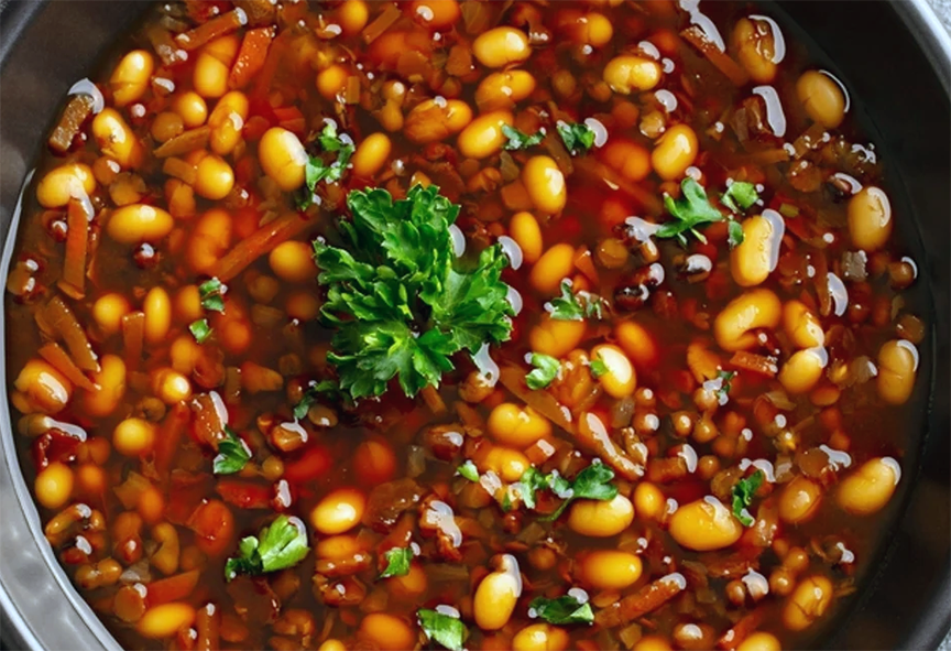 bell pepper and bean stew in a bowl garnished with a sprig of curly parsley