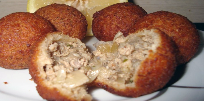 koupes, deep fried meat in flour paste crust with one split open to reveal the filling