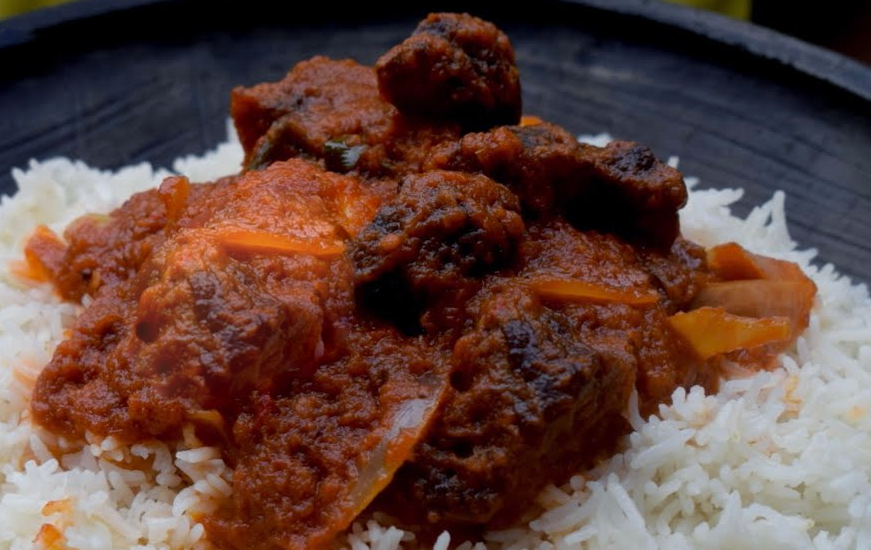 beef in a tomato and locust bean sauce served on a bed of rice