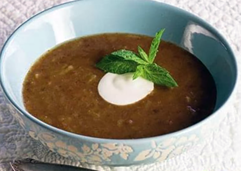 Estonian sweet rye bread soup in a bowl garnished with sour cream and a sprig of mint
