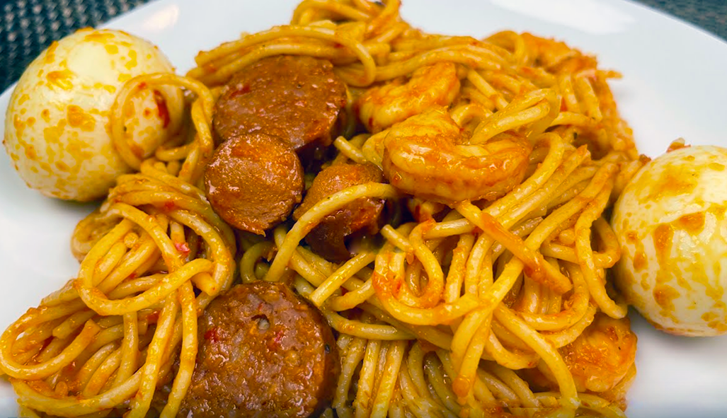 spaghetti in a spicy tomato sauce served with hard-boiled eggs, sausage and prawns