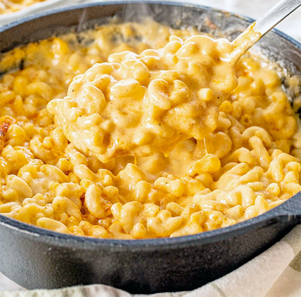 macaroni cheese in a metal casserole lifted with a spoon