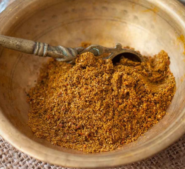 malvani masala spice blend in a bronze vessel with a spoon
