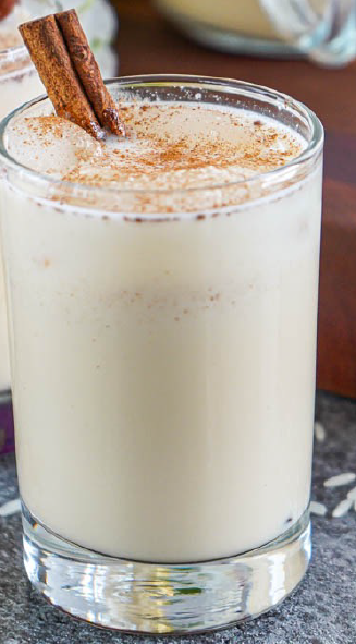 rice horchata drink in a glass garnished with ground cinnamon and a cinnamon stick