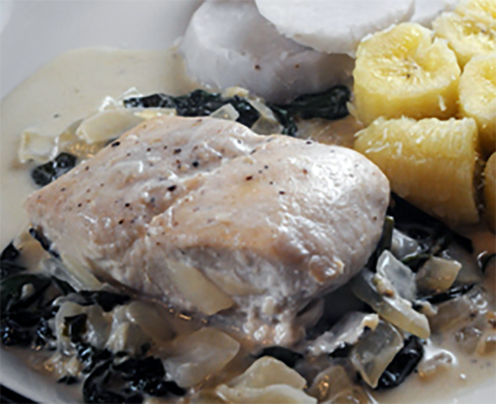 mahimahi stewed in coconut cream with taro leaves served on a plate with bananas and taro