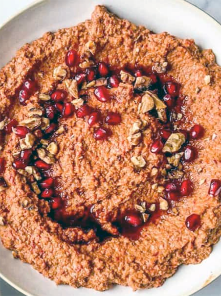 muhammara pepper and walnut dip garnished with pine nuts and pomegranates served in a bowl</a>