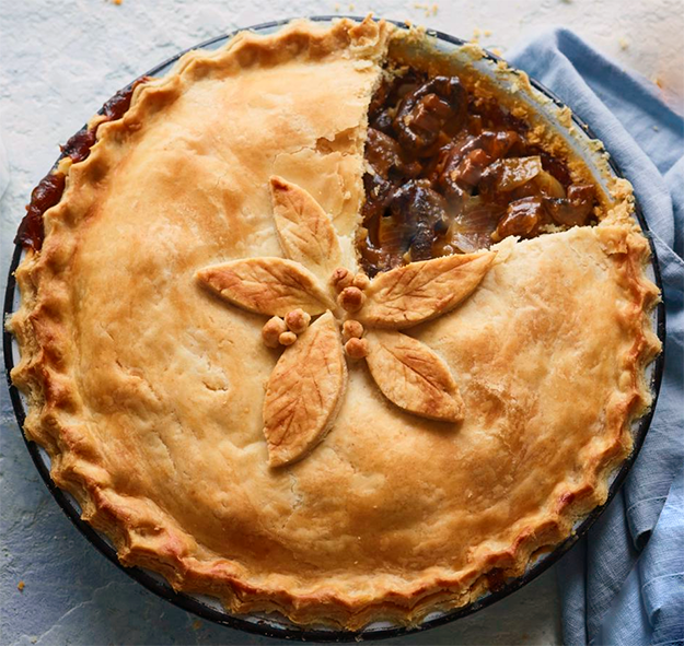 deep mushroom, cheese and sea aster pie with a wedge of crust removed to reveal the filling