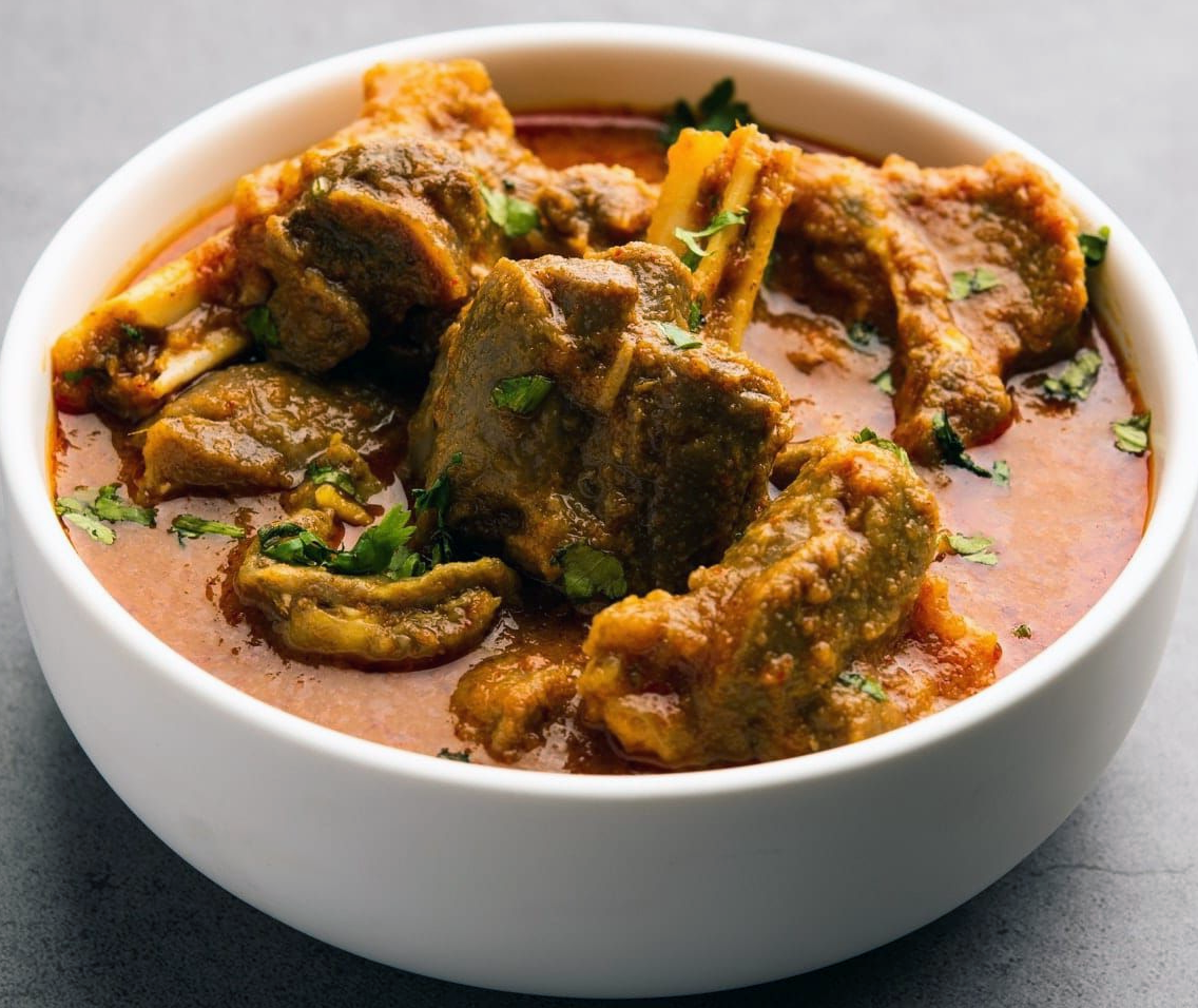 pepper goat meat stew with chironji nuts served in a white bowl