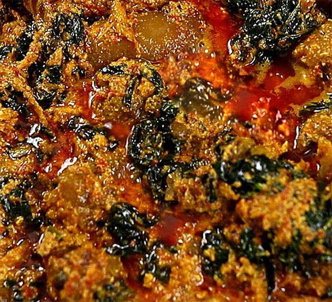 stew of smoked meat, hibiscus leaves and egusi powder in a red palm oil base