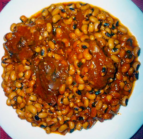 stew of black eyed beans and beef in a tomato sauce with onion and hot chilli served on a white plate