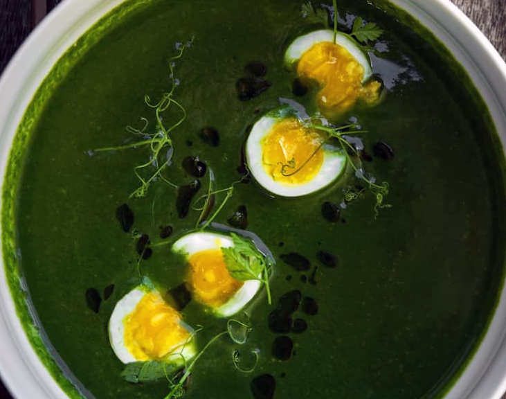 nettle soup topped with hard-boiled eggs served in a bowl