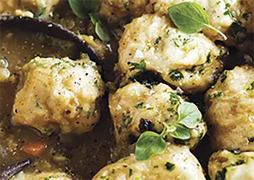 Norfolk yeasted swimmer dumplings cooked on top of a stew with a garnish of fresh oregano