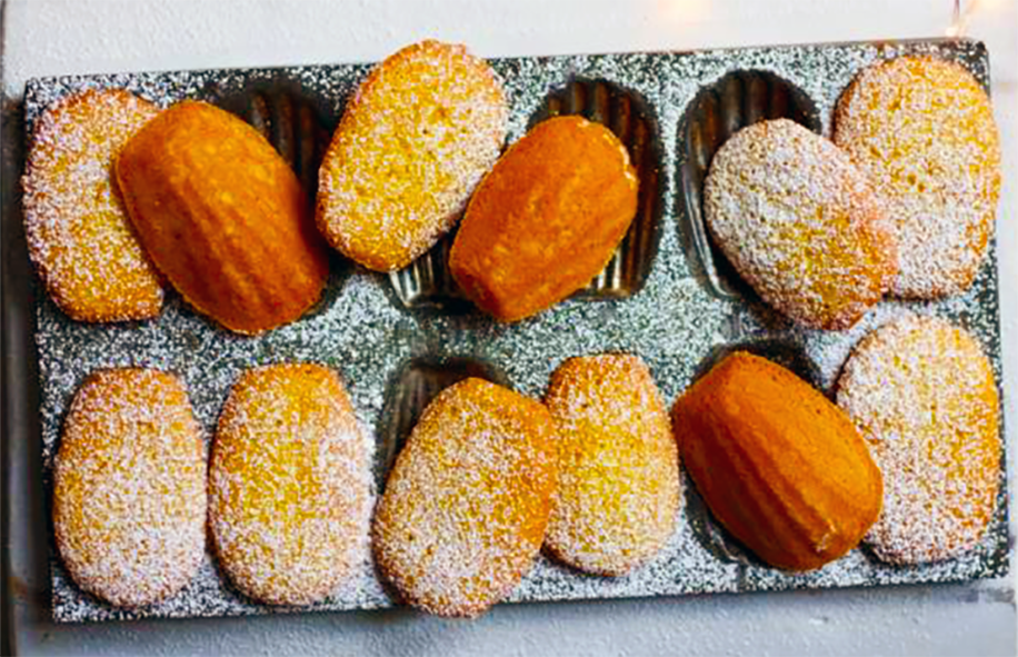 orange and cardamom madeleines served on a madeleine tin