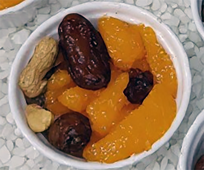 oranges, dates and peanuts over grated coconut served in a ramekin