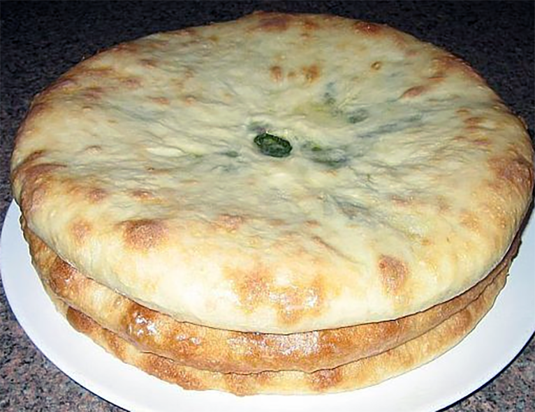 three ossetian pies with ramson leaves and cheese filling on a plate