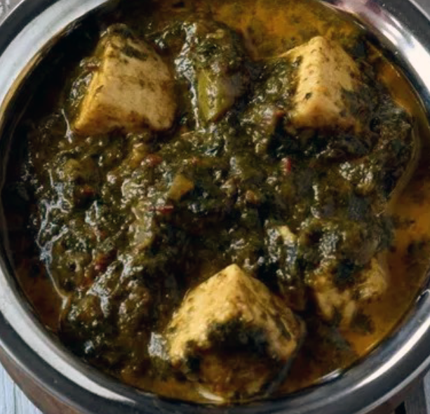 paneer cubes in a spicy spinach sauce served in a steel bowl
