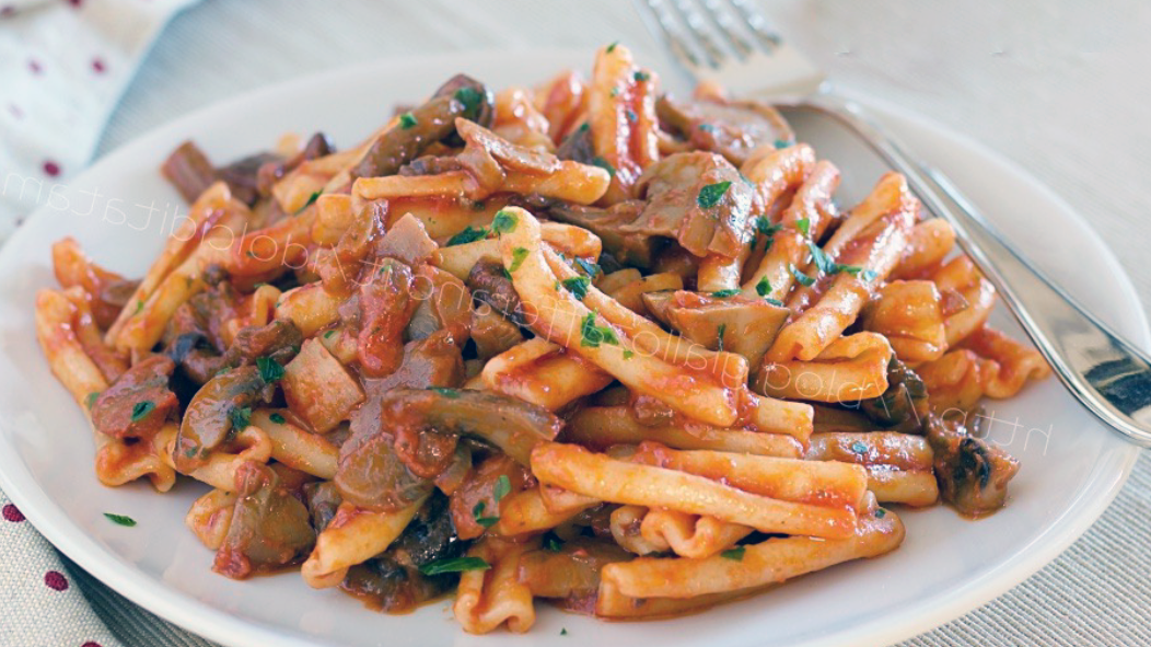 casarecce pasta tossed with mixed mushroom sauce and served on a white plate