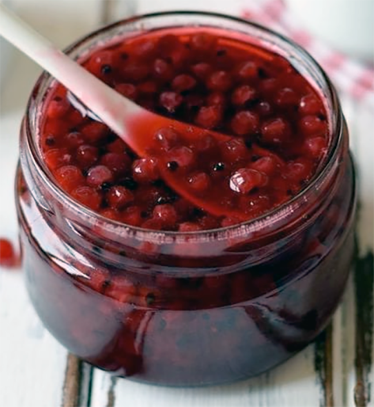 vinegar-pickled redcurrants in a jar with a wooden spoon