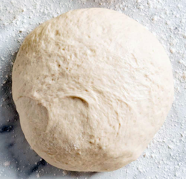 Ball of pizza dough resting on a floured work surface