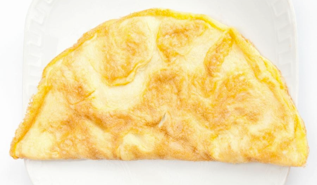 Classic plain French omelette folded into a half moon and served on a white plate