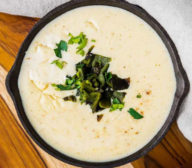 poblano queso, cheese sauce with poblano chillies in a skillet with a poblano chilli garnish