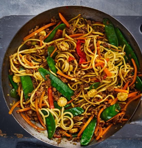 Pork noodle stir fry with mangetout in a wok