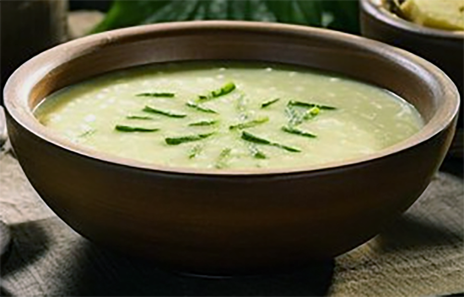 breadfruit and milk soup topped with green beans in a wooden bowl