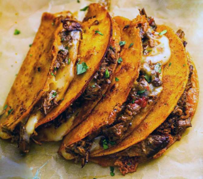 tacos with a cheese and slow-cooked shredded birria beef filling; four set lying on each other