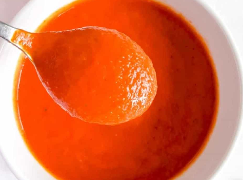 red bell pepper coulis lifted from a bowl on a spoon
