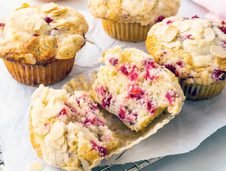 redcurrant muffins on a cooling rack with one split open to reveal the centre