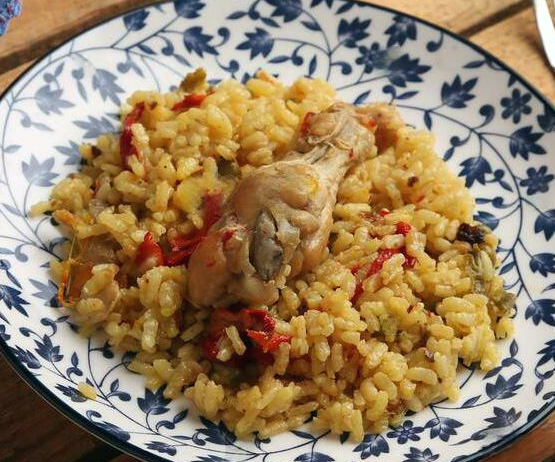 rice bujambura topped with a chicken leg on a plate