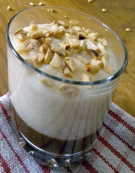 rice pudding with chopped peanut garnish served on a bed of caremel in a tumbler