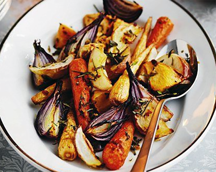mix roasted vegetables on a white plate with a spoon