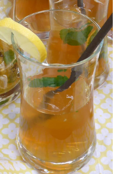 iced rooibos tea in a glass with ice and a lemon balm leaf