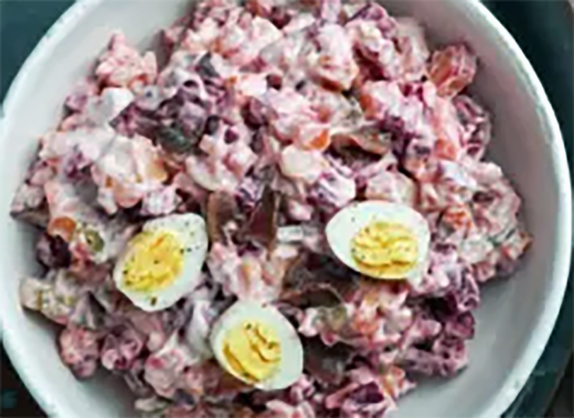 Estonian potato and beetroot salad with herring topped with hard-boiled eggs and served in a bowl