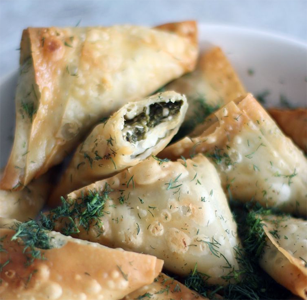 triangular spinach-filled turnovers in a bowl
