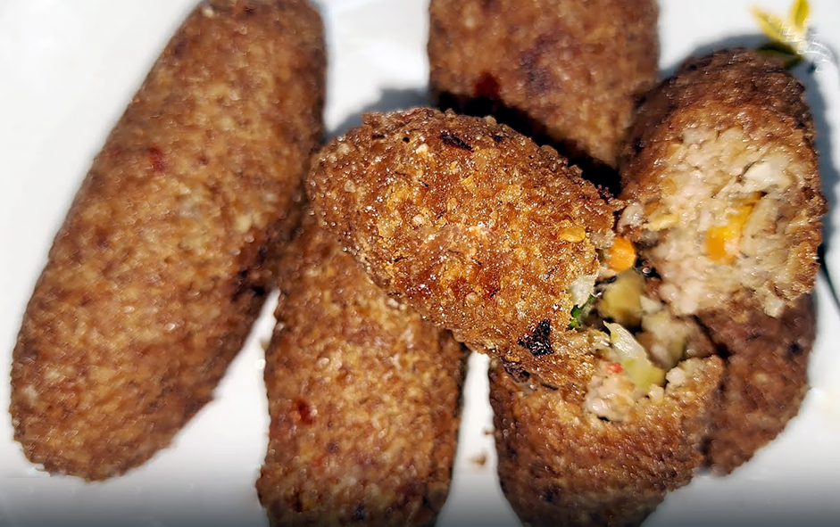 Sierra leonean style kibbeh served on a plate with one sliced to reveal the centre