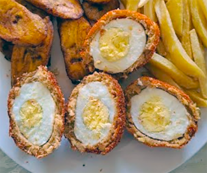 four sierra leonean scotch eggs served on a plate with fried plantain slices and fries