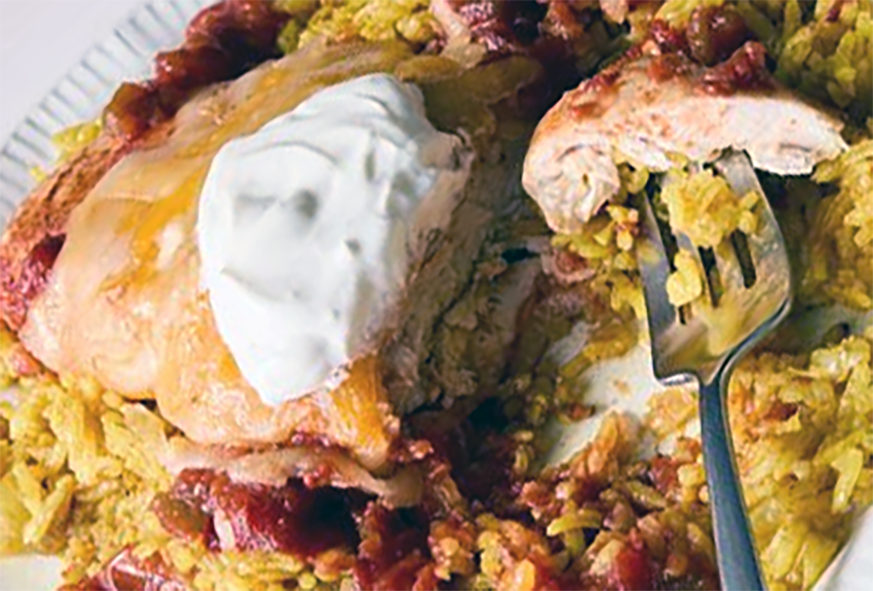 chicken breast cooked in salsa served topped with melted cheese and sour cream on a bed of rice