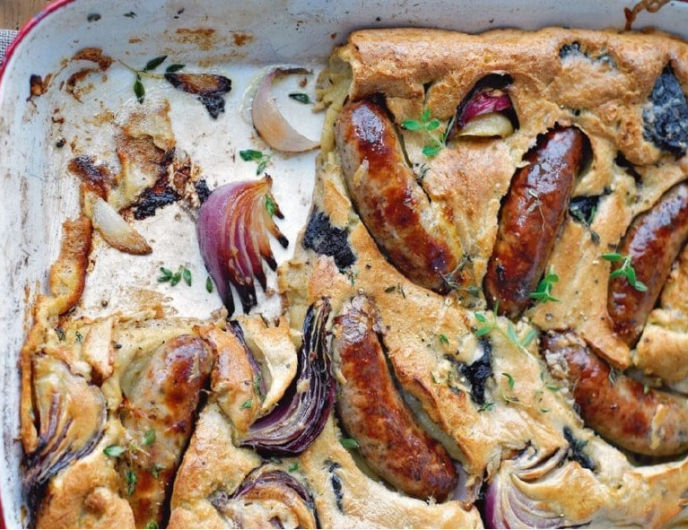 sausage and guinness toad in the hole in a baking dish with a square piece removed